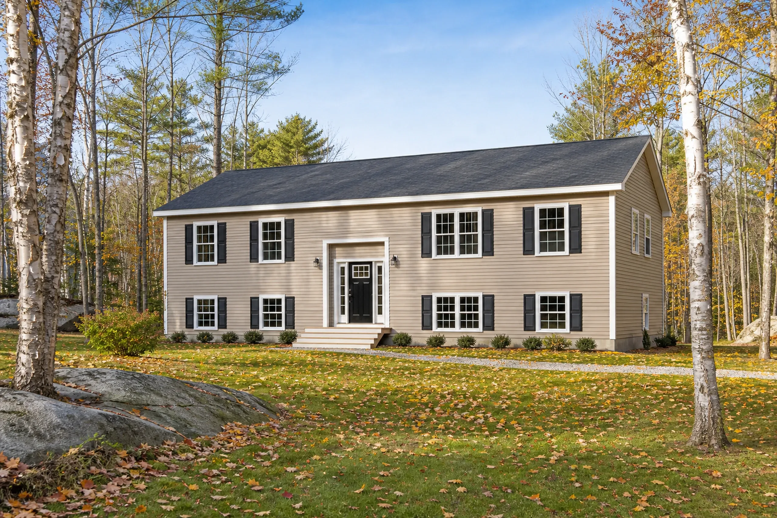 Gray, ME post-1970 home: raised ranch on a wooded lot with new tan vinyl lap siding, white trim and dark shutters, early fall leaves on the lawn.